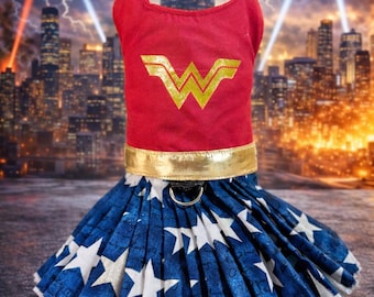 May include: A red and gold Wonder Woman pet costume. The top is red with a gold "W" emblem. The skirt is blue with white stars. Includes gold arm cuffs. The costume is designed for a dog or cat.