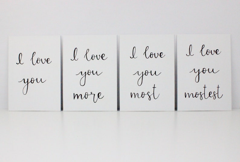 Puede incluir: Cuatro tarjetas blancas con caligraf&iacute;a negra que dice "Te amo", "Te amo m&aacute;s", "Te amo m&aacute;s", y "Te amo m&aacute;s que nada".