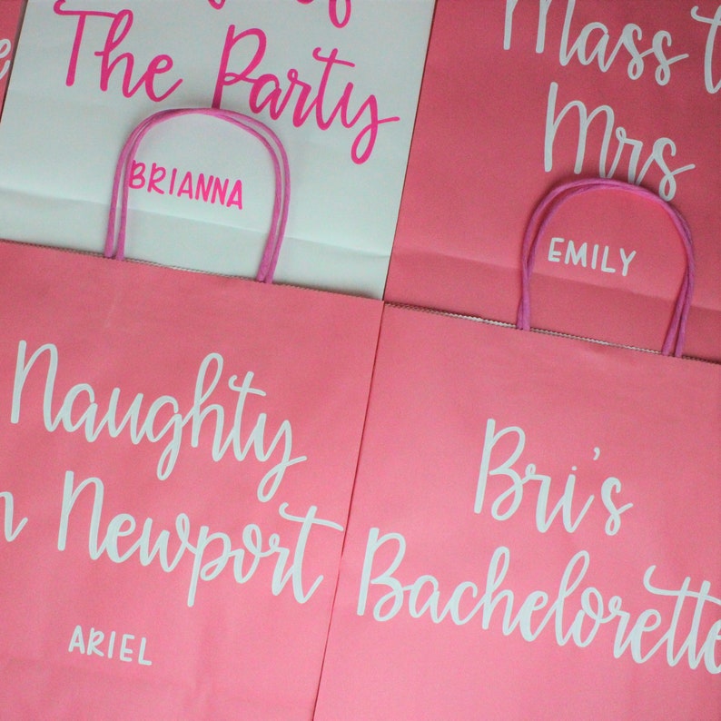 Pu&ograve; includere: Quattro sacchetti regalo rosa con scritte bianche. I sacchetti sono etichettati con "The Party Brianna", "Mass to Mrs Emily", "Naughty in Newport Ariel" e "Bri's Bachelorette".