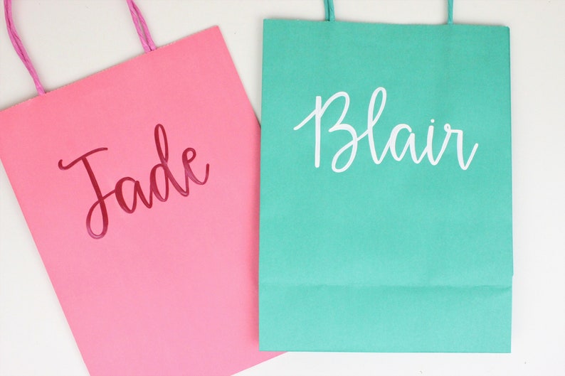 Pu&ograve; includere: Due sacchetti regalo, uno rosa con il nome "Jade" in lettere rosse e uno verde acqua con il nome "Blair" in lettere bianche.