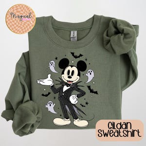 Pu&ograve; includere: Felpa Gildan verde oliva con un personaggio dei cartoni animati in un abito a righe bianche e nere, orecchie di Topolino e un papillon bianco. Il design include pipistrelli, fantasmi e stelle. La felpa ha il testo "Gildan Sweatshirt".