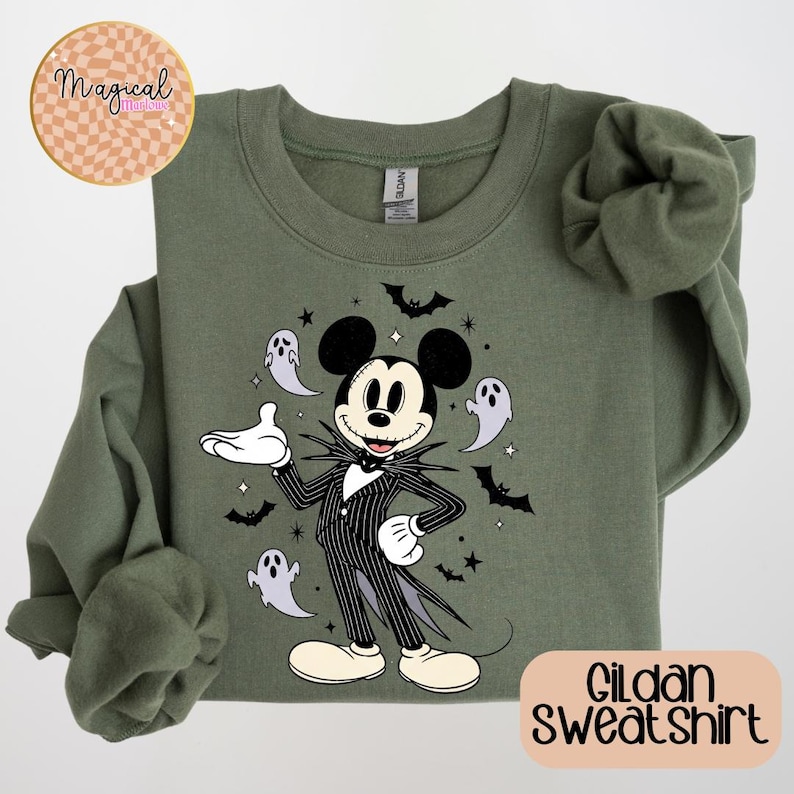 Pu&ograve; includere: Felpa Gildan verde oliva con un personaggio dei cartoni animati in un abito a righe bianche e nere, orecchie di Topolino e un papillon bianco. Il design include pipistrelli, fantasmi e stelle. La felpa ha il testo "Gildan Sweatshirt".