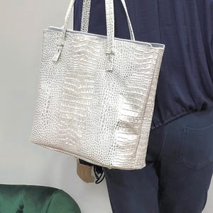 Bolso tote de piel repujada color crema nacarada con estampado de cocodrilo, ribete color ostra, bolsillos, cierre para llaves, cierre magnético o cierre de cremallera.