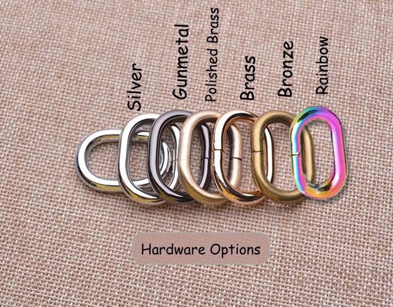 May include: A collection of six oval metal rings arranged in a row, labeled Hardware Options. The finishes include silver, gunmetal, polished brass, brass, bronze, and a multi-colored rainbow finish. Each ring features a smooth, rounded surface.