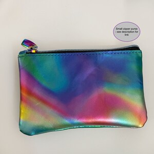 May include: A small rectangular zipper purse with a metallic iridescent finish featuring a spectrum of colors including blue, green, purple, and pink. The purse has a black zipper closure and includes the text Small zipper purse - see description for link.