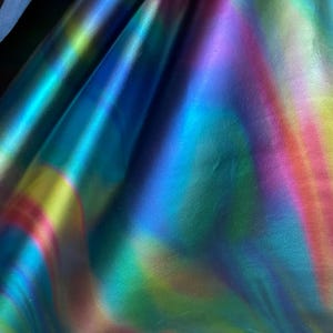 Puede incluir: Primer plano de cuero iridiscente con un esquema de color azul, verde, amarillo y rosa. El cuero tiene un acabado liso y brillante.