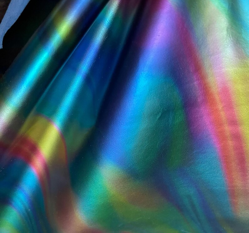 Puede incluir: Primer plano de cuero iridiscente con un esquema de color azul, verde, amarillo y rosa. El cuero tiene un acabado liso y brillante.
