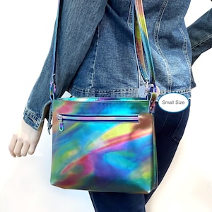 May include: A small iridescent rainbow crossbody bag with a zipper closure. The bag has a long adjustable strap and is made of a shiny, holographic material. "Small Size" is written on a white tag attached to the bag.