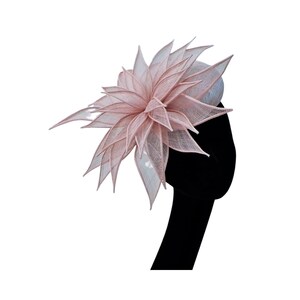 Op de afbeelding: Een roze en witte fascinator met een groot, gelaagd bloemmotief. De bloem is gemaakt van een delicate, doorschijnende stof.