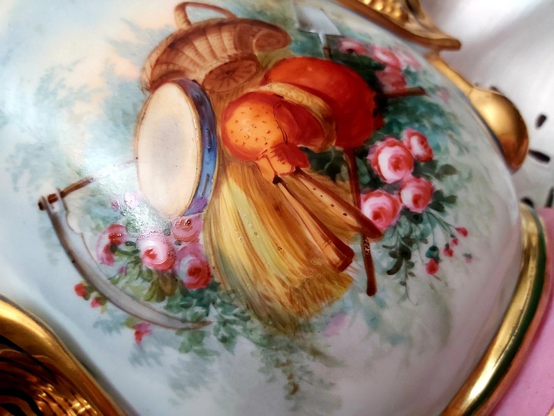 K&ouml;nnte beinhalten: Eine antike Porzellanvase mit handbemaltem Motiv eines Korbes, einer Trommel und Blumen. Die Vase ist mit goldenen Akzenten verziert und hat ein zartes Blumenmuster.