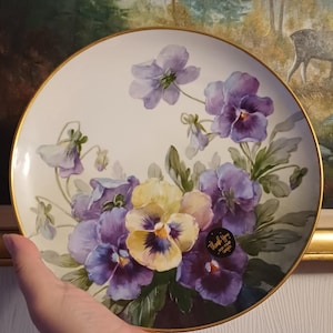 Könnte beinhalten: Ein dekorativer Teller mit einem Blumendesign aus lila und gelben Stiefmütterchen und grünen Blättern. Der Teller hat einen goldenen Rand und einen Aufkleber mit der Aufschrift "Vielen Dank für Ihre Bestellung."