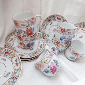 May include: A set of six vintage porcelain teacups and saucers with floral patterns in shades of pink, blue, yellow, and green. The cups and saucers have gold trim and are in excellent condition.