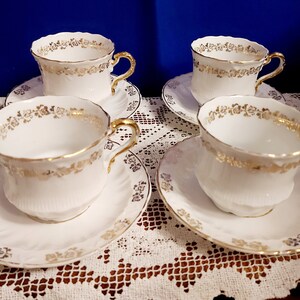 May include: Set of four white teacups and saucers with gold trim and floral designs.