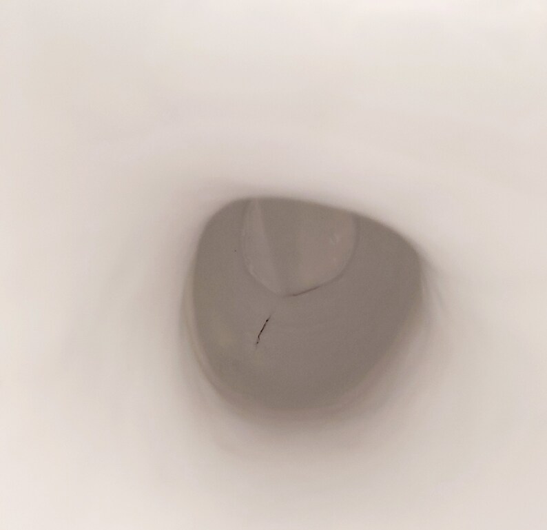 K&ouml;nnte beinhalten: Nahaufnahme einer wei&szlig;en Toilettensch&uuml;ssel mit einem kleinen Riss im Porzellan.