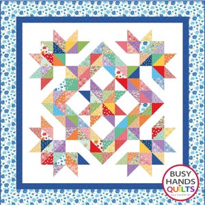 May include: A colorful quilt with a star pattern, featuring various fabric patterns in red, orange, yellow, green, blue, and purple. The quilt has a white background with a blue border and floral pattern. The quilt is handmade.