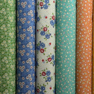 May include: A collection of fabric rolls in various colors, each adorned with floral patterns. The colors include lavender, green, blue, white, teal, orange, and yellow. The floral designs vary, featuring small daisies and other stylized flowers.