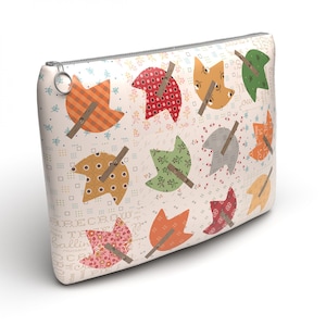 May include: A rectangular zippered pouch featuring a cream-colored background with a repeating pattern of stylized leaves in various colors including orange, red, green, and yellow, each accented with a small brown stick and subtle text details.