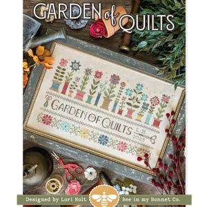 May include: A framed cross-stitch sampler with the text "GARDEN of QUILTS" and floral designs. The sampler features colorful flowers in pots and spools of thread. The design is by Lori Holt of Bee in my Bonnet Co.