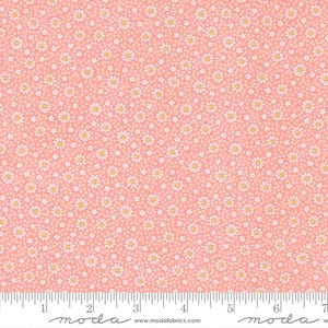 May include: A cotton fabric featuring a repeating pattern of small white daisies with yellow centres on a soft pink background. A white ruler is visible at the bottom edge, showing measurements in centimetres up to 18 cm for scale reference.