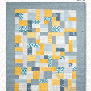 May include: A patchwork quilt with a geometric design in shades of yellow, blue, gray, and white. The quilt features a variety of patterns and textures, with a solid gray border. The text "YELLOW BRICK ROAD" is at the bottom.