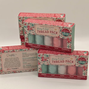 May include: Several thread packs are displayed, each containing six spools of thread in various colors. The boxes are decorated with a floral pattern and the text "Berry & Sage Thread Pack." The thread colors include Alpine, Leaf, Latte, Coral, and Jazzberry.