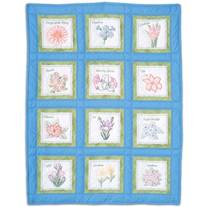 May include: A blue floral quilt with embroidered flower squares. Each square features a different flower, including daisies, pansies, and lilies, with the flower's name embroidered above. The quilt has a light blue border.