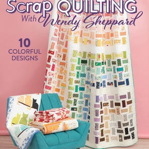 May include: A colorful quilt book cover with the title "Scrap Quilting With Wendy Sheppard" and the text "10 Colorful Designs." A teal armchair holds several folded quilts. A large, rainbow-colored quilt hangs in the background.
