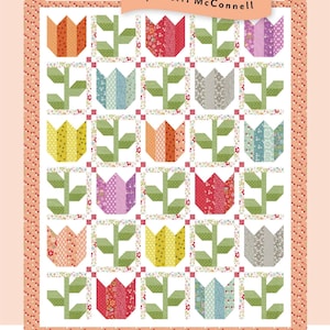 May include: A colorful quilt with a tulip and vine pattern. The quilt features a grid of tulip blocks in various colors, including orange, red, yellow, and purple. The quilt is bordered with a floral print and includes the text "A Quilting Life" and "Tulip & Vine".