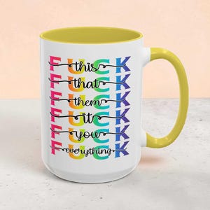 May include: White ceramic mug with a yellow handle and interior. The mug features the text "F*ck this, that, them, it, you, everything" in a rainbow of colors.