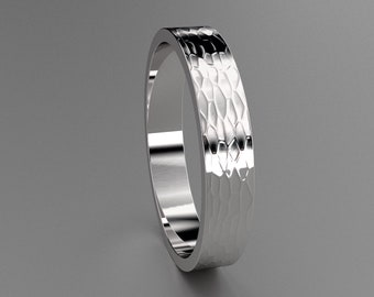 May include: A silver ring with a textured, hammered finish. The ring has a flat profile and a polished, reflective surface. The design features a repeating pattern of small, irregular shapes. The ring is displayed against a grey background.