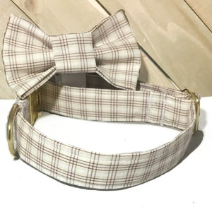 May include: A beige and brown plaid dog collar with a matching bow tie. The collar has a gold metal buckle.