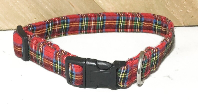 May include: Red and green plaid dog collar with a black plastic buckle and a silver metal D-ring.