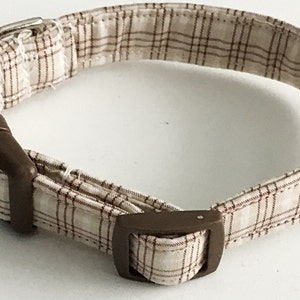 May include: A brown and white plaid dog collar with a brown plastic buckle.