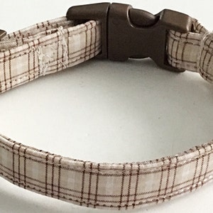 May include: A brown and white plaid dog collar with a brown plastic buckle.