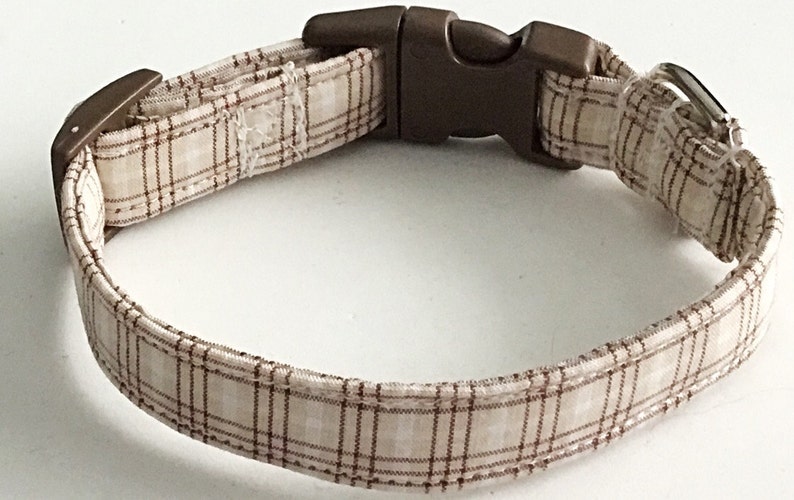 May include: A brown and white plaid dog collar with a brown plastic buckle.