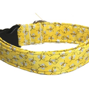 May include: Yellow dog collar with a pattern of black and silver bees. The collar has a black plastic buckle.