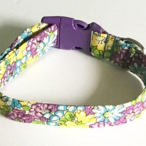 Peut inclure: Un collier pour animal en tissu arborant un motif floral aux fleurs jaunes, violettes et bleu clair sur fond blanc. Le collier est doté d'une boucle à dégagement latéral en plastique violet, d'un curseur de réglage en plastique et d'un anneau en D.