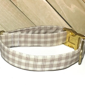 May include: A brown and white plaid dog collar with a gold metal buckle and D-ring.