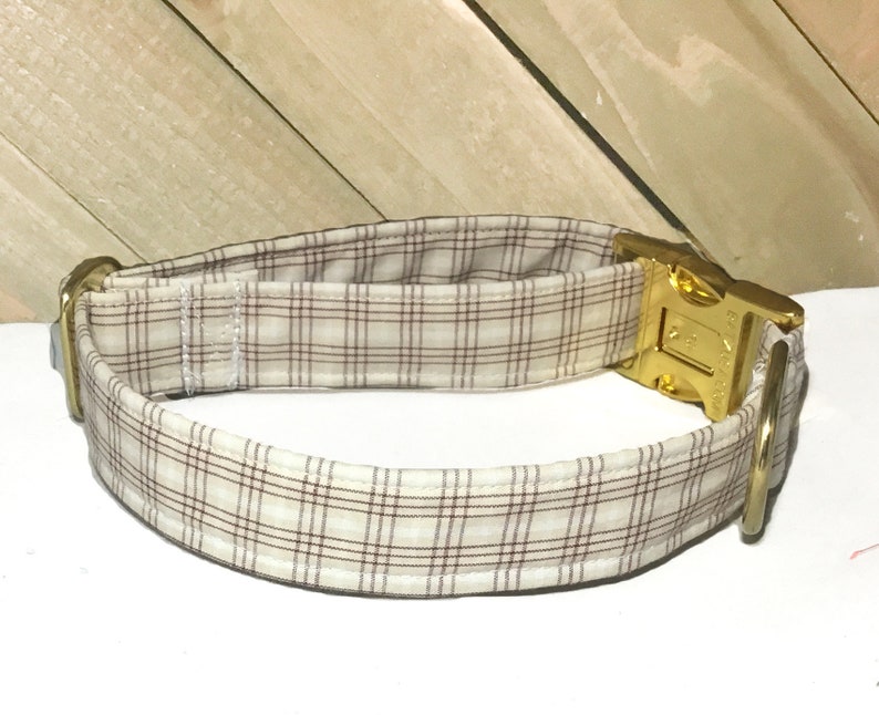 May include: A brown and white plaid dog collar with a gold metal buckle and D-ring.