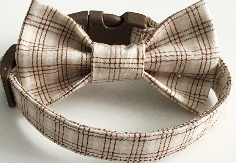 May include: A brown and beige plaid dog collar with a matching bow tie. The collar has a plastic buckle closure.
