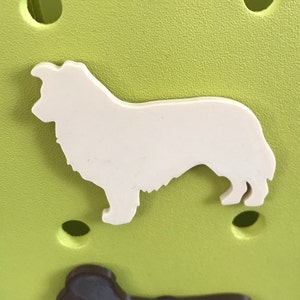 May include: White silhouette of a dog on a green background. The dog is standing with its head turned to the left.