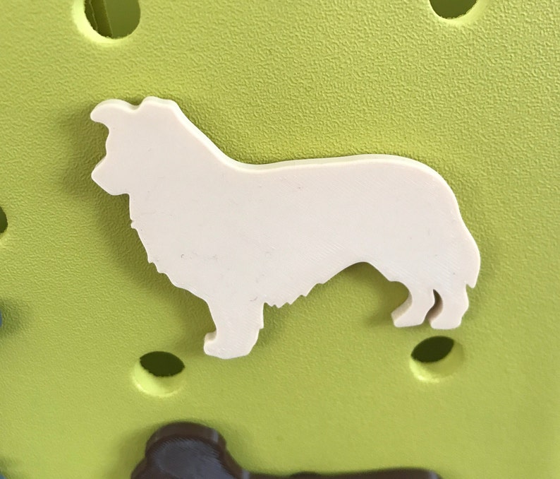 May include: White silhouette of a dog on a green background. The dog is standing with its head turned to the left.