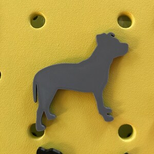 May include: A gray silhouette of a dog standing on a yellow background.