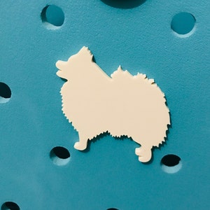 May include: White silhouette of a dog on a blue background. The dog is facing the left side of the image. The background has a textured surface with small holes.