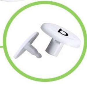 May include: Two white plastic push pins with a black letter 'B' on the top of one pin.