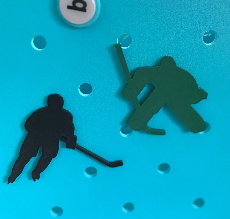 May include: Two black silhouettes of hockey players on a bright blue background. One player is holding a hockey stick and the other is in a goalie stance.