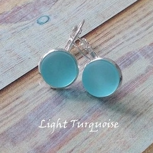 May include: A pair of light turquoise glass earrings with silver leverback closures.