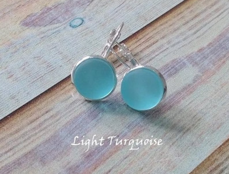 May include: A pair of light turquoise glass earrings with silver leverback closures.
