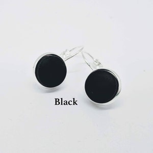 May include: A pair of silver dangle earrings with black round cabochon stones. The earrings are labeled "Black".