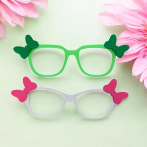 May include: Two pairs of glasses with butterfly-shaped accents. One pair has green frames and green butterfly accents, the other has white frames and pink butterfly accents.